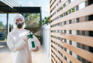 Disinfection specialist staff in personal protective equipment (ppe) suit, gloves, mask and face shield, cleaning Quarantine area with a bottle of pressurized spray disinfectant to remove covid-19.
