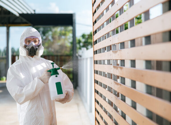 Disinfection specialist staff in personal protective equipment (ppe) suit, gloves, mask and face shield, cleaning Quarantine area with a bottle of pressurized spray disinfectant to remove covid-19.