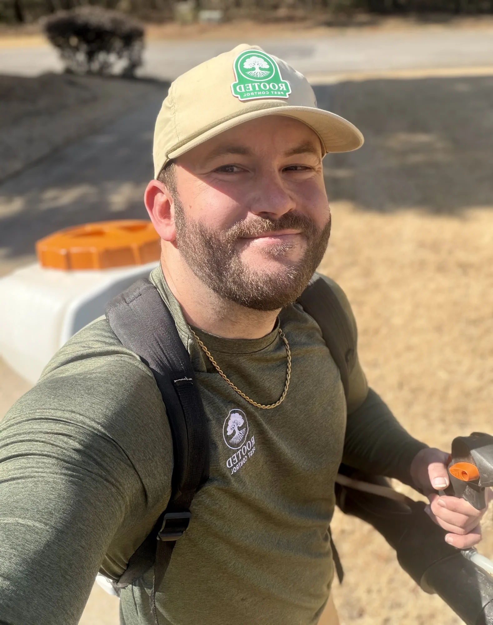 Rooted Pest Control technician with a backpack sprayer