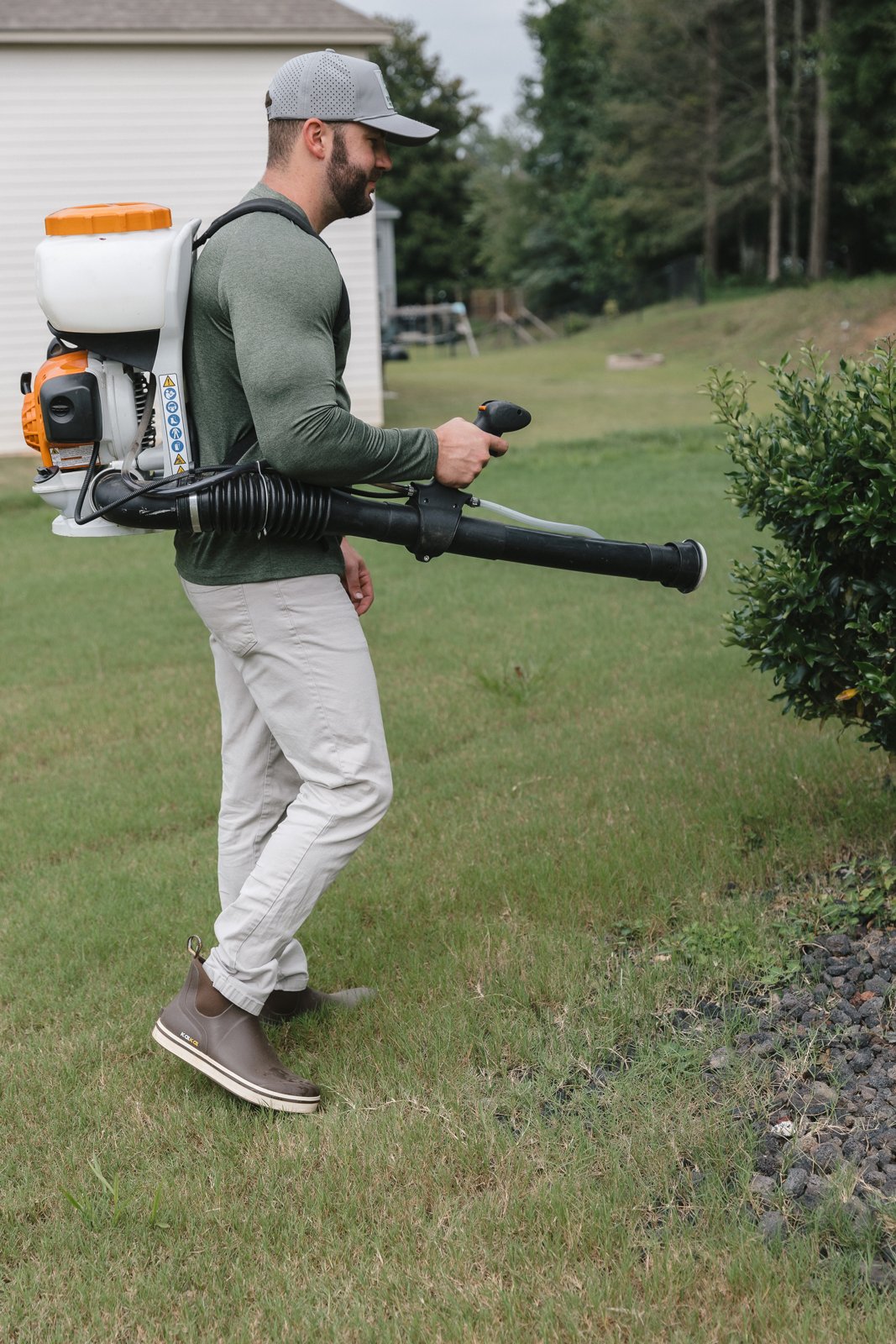 Rooted Pest Control technician fogging shrubs for mosquitoes in a West Georgia backyard.