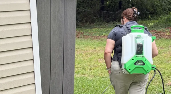 technician-backpack-sprayer-exterior-perimeter-1920 Rooted technician treating a home's exterior perimeter for mosquitoes.