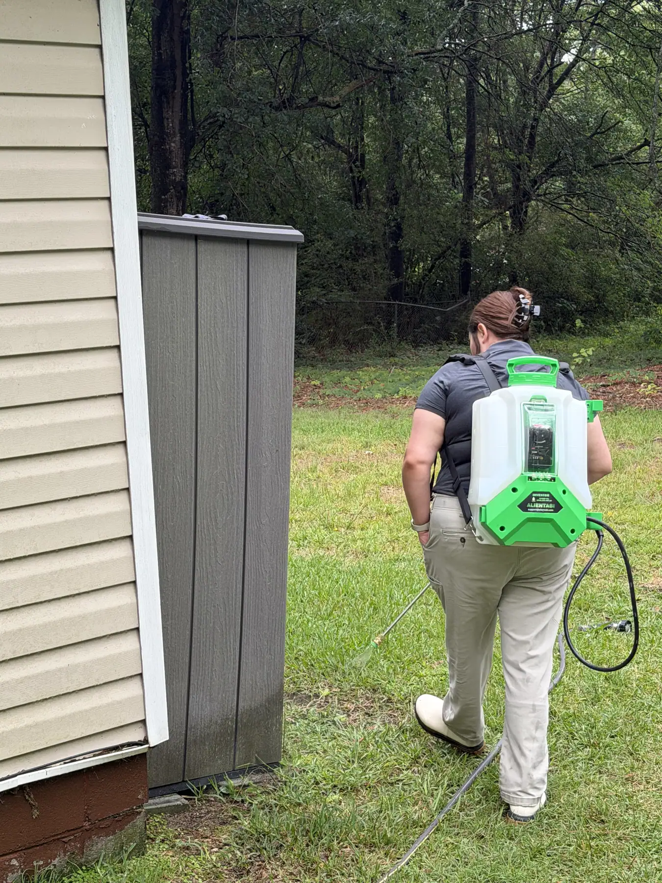 Rooted technician treating a home's exterior perimeter for mosquitoes.