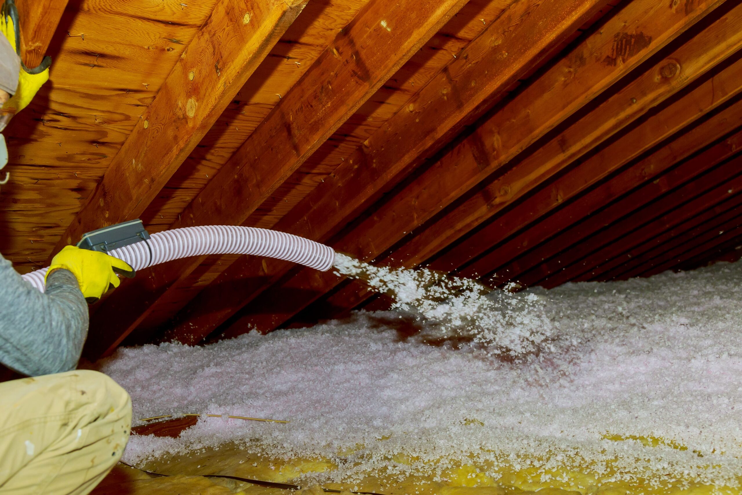 Technician blowing fiberglass attic insulation